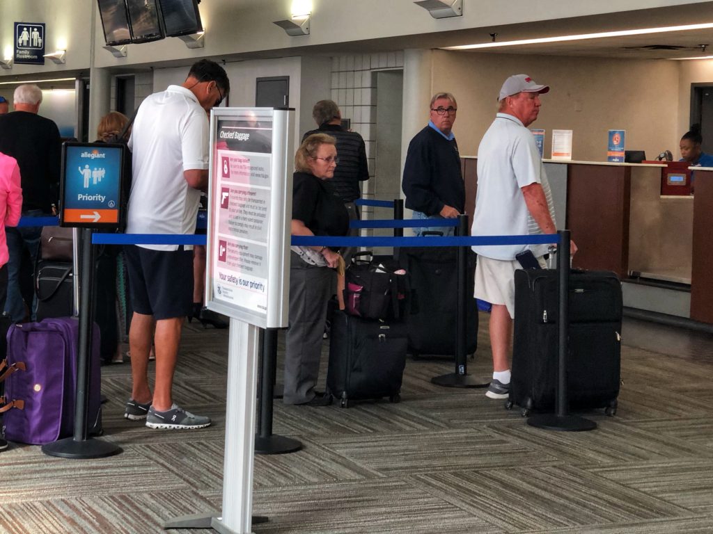 people waiting in line to check bags at the airport